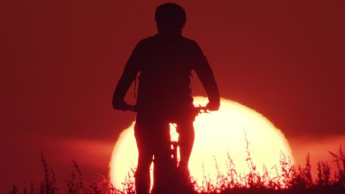 日落时骑自行车的人举起自行车的剪影