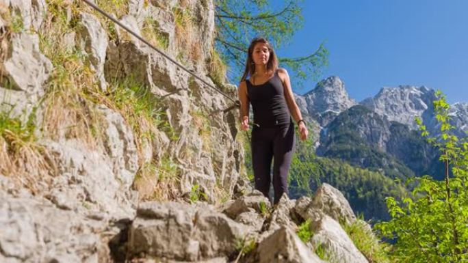 运动活跃的女人在山区的岩石小径上散步