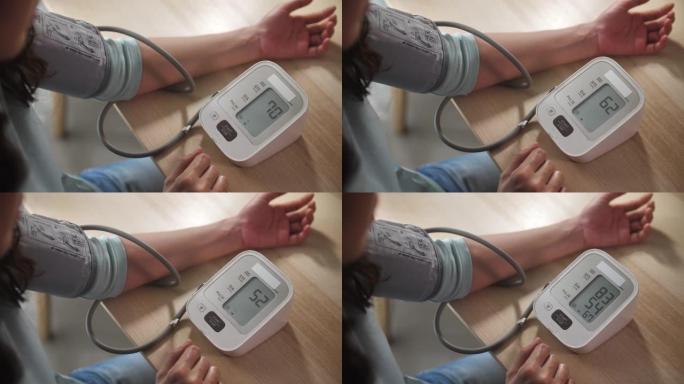 使用监视器的亚洲妇女在家中测量自己的血压