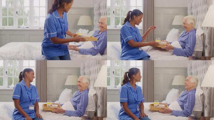 穿着制服的女护理人员带老人在家吃早餐，躺在托盘上的床上