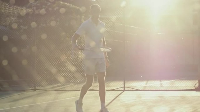 适合成熟的男人带着球拍和网球走进网球场