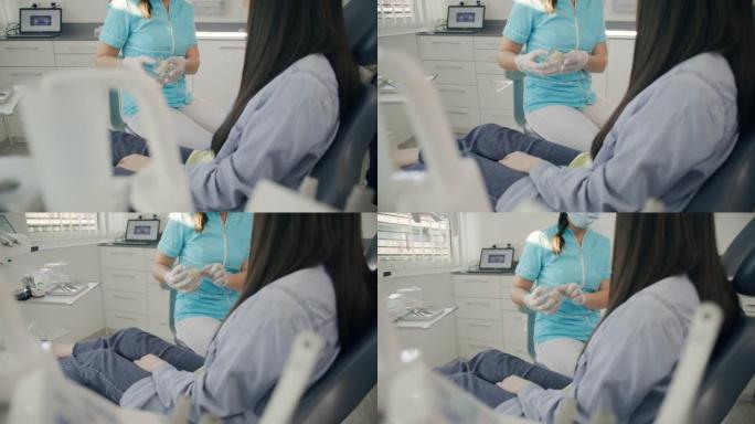 MS女牙医在与女患者交谈时使用牙齿模型