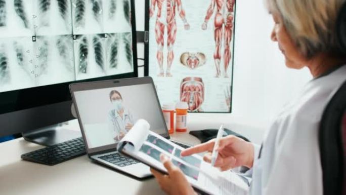 远程讨论患者病例，高级医生使用笔记本电脑在线视频呼叫远程与医生交谈