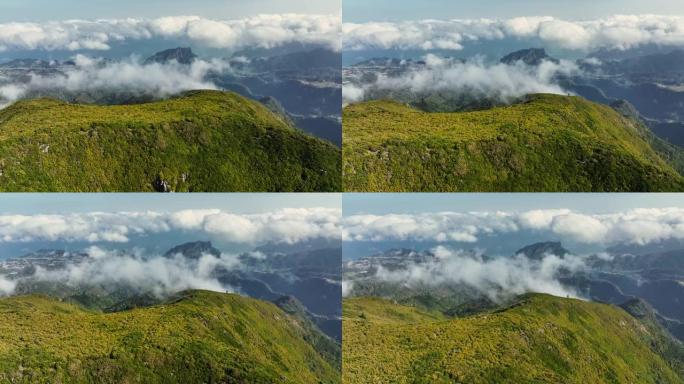 在马德拉的皮科鲁沃飞越绿色的山脉和云层。马德拉岛山区的大早晨鸟瞰图。UHD, 4K