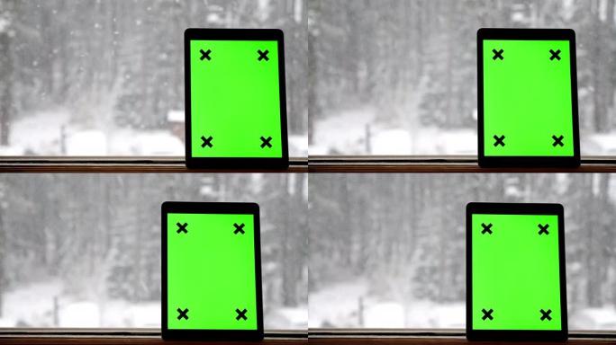 降雪时手持绿色屏幕的数字平板电脑
