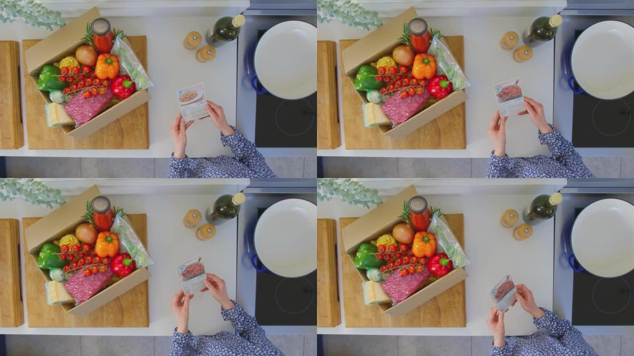从女人的上方看，用食谱卡和盒装配料计划用餐-慢动作拍摄