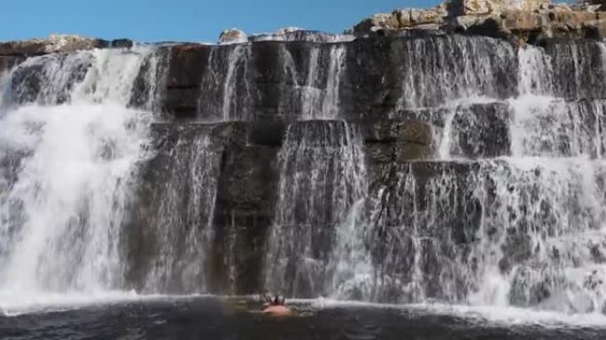 南非东开普省姆坎巴蒂自然保护区，一对夫妇在壮丽的马蹄瀑布中游泳的鸟瞰图