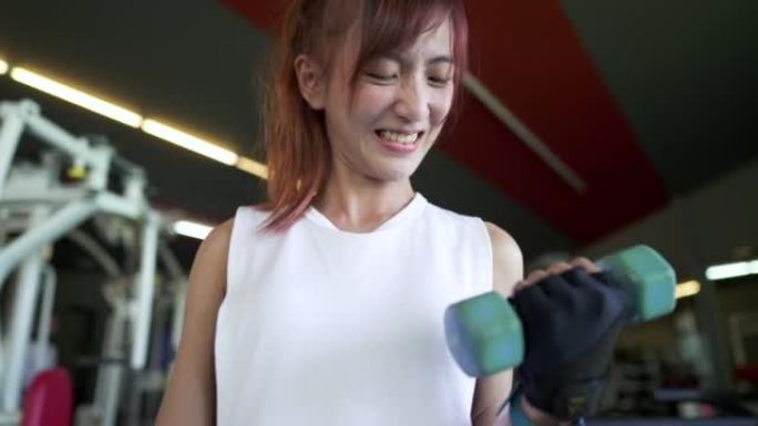 亚洲女子在体育馆用哑铃进行举重运动
