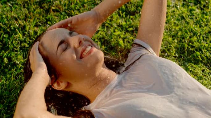 超级SLO MO年轻女子躺在草地上喜欢喷水