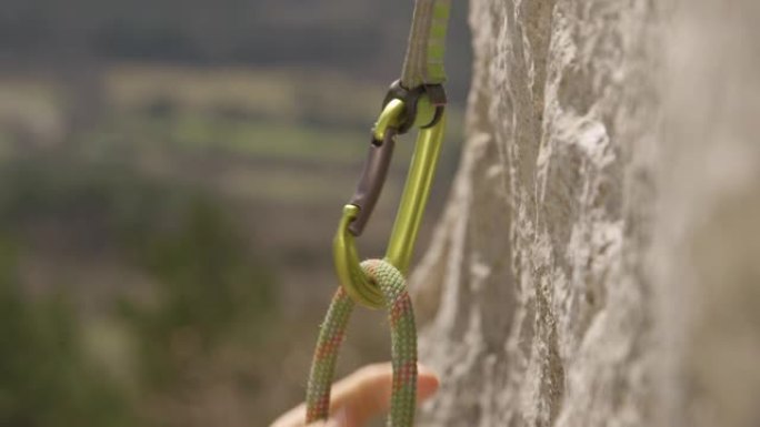 特写镜头，dop: 适合女性的顶部绳索将她的绳索套入安全登山扣中。