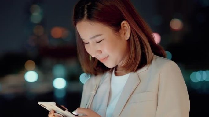 美丽的亚洲女人晚上劳累后用手机给丈夫发短信。