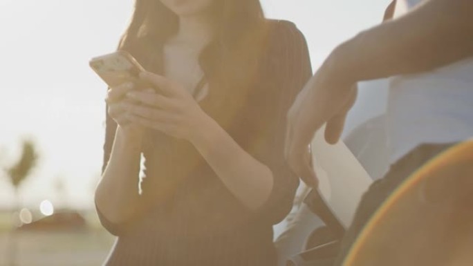 SLO MO年轻女子在男友为电动汽车充电时使用智能手机