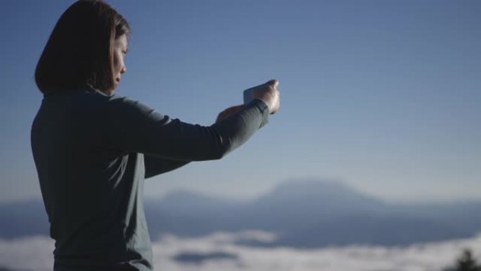 女旅行者在山地自然国家公园用智能手机拍摄风景秀丽的照片