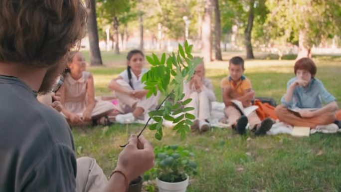 男子在户外向好奇的孩子教授生物学