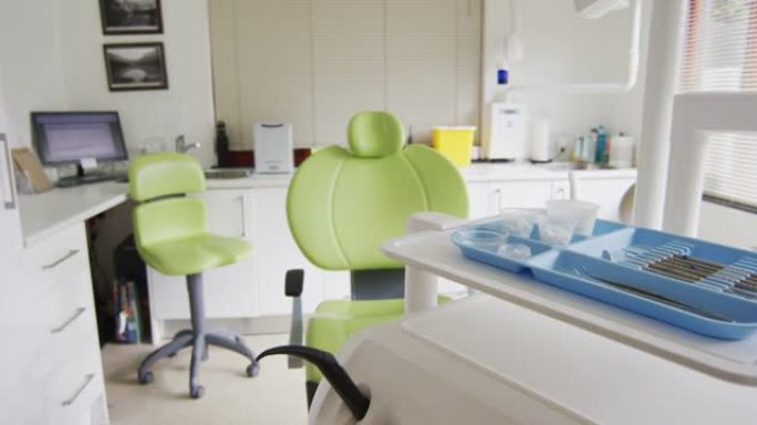 牙科诊所的空内部，配有绿色牙科椅和工具