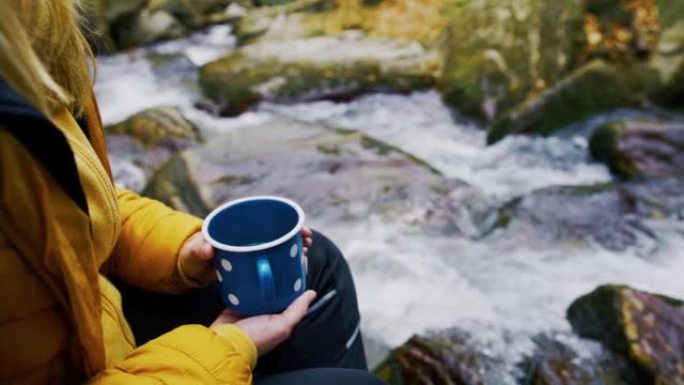 女人放松并在流水旁拿着茶杯