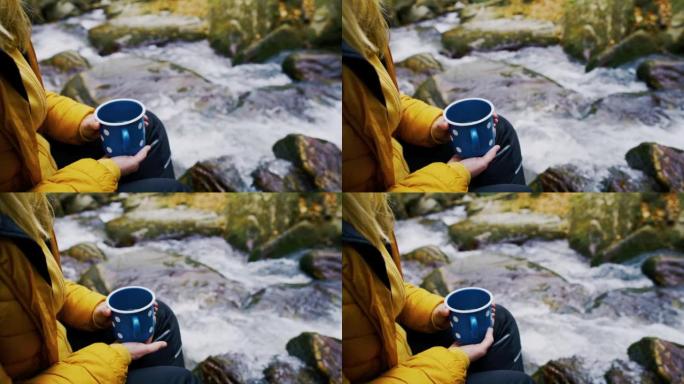 女人放松并在流水旁拿着茶杯