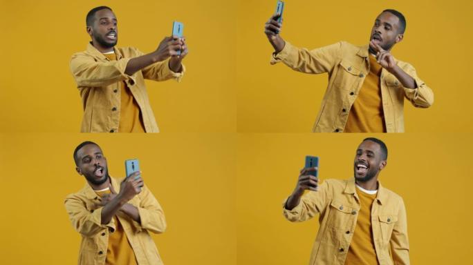 英俊的美国黑人男子在黄色背景下用移动相机自拍的肖像