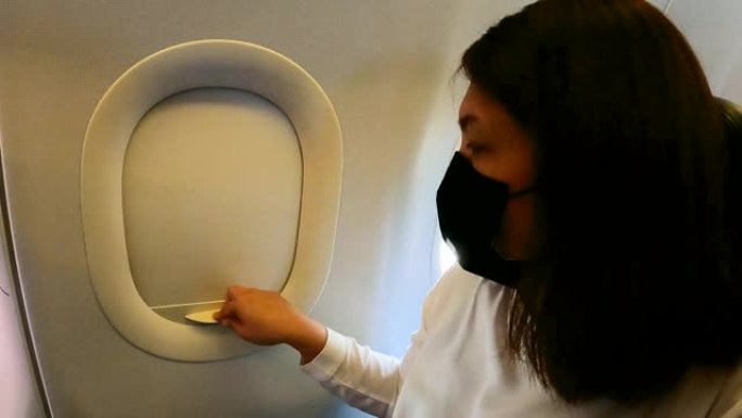戴面罩的女乘客关闭飞机窗户休息