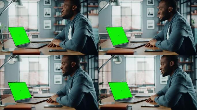 英俊的黑人非洲裔美国专家在笔记本电脑上通过视频通话聊天，并在家庭客厅显示绿屏模型。自由职业者在社交网