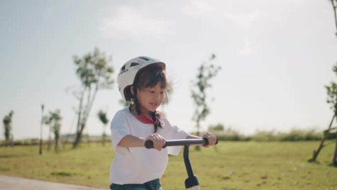 骑平衡自行车的女孩，带着运动头盔骑自行车玩得开心