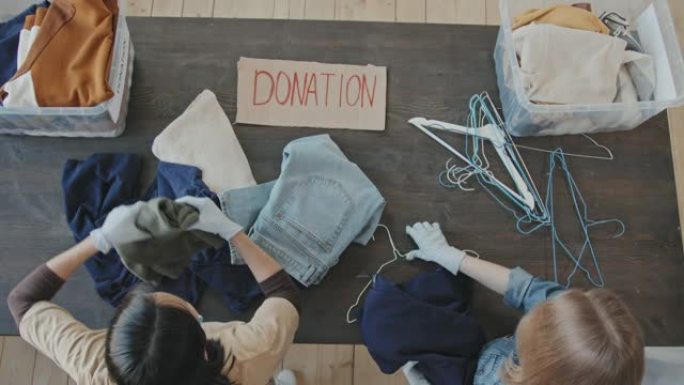 志愿者为慈善事业折叠捐赠的衣服的俯视图