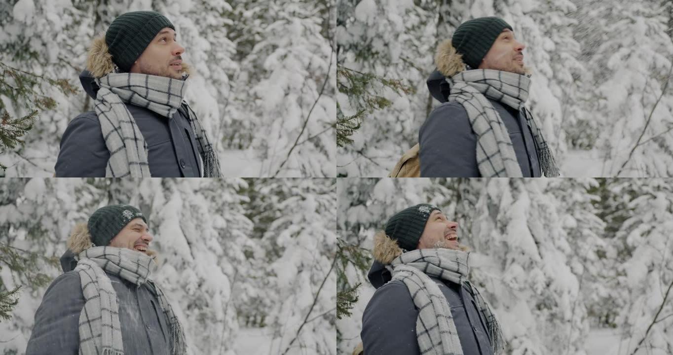 站在冬季森林里的无忧无虑的游客的慢动作肖像笑着享受降雪