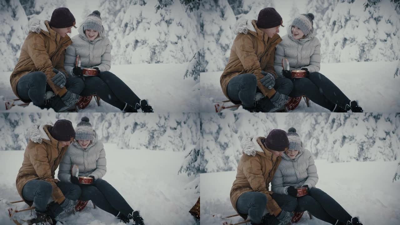 年轻夫妇在白雪覆盖的森林上打开饼干的容器盒