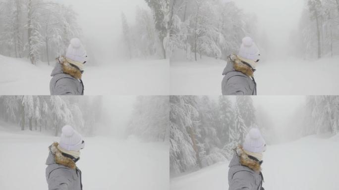自拍照: 女人在一条经过修饰的斜坡上滑雪板，穿过雾蒙蒙的森林。