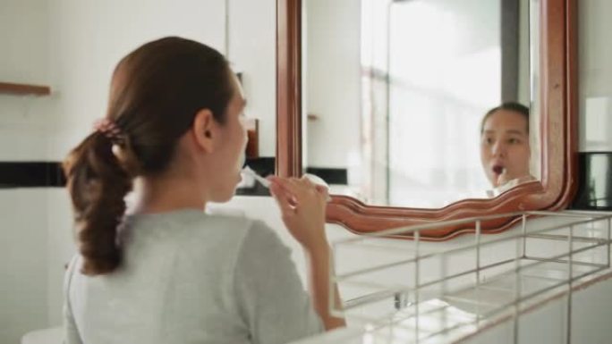 亚洲妇女刷牙梳洗化妆洗漱间上班照镜子