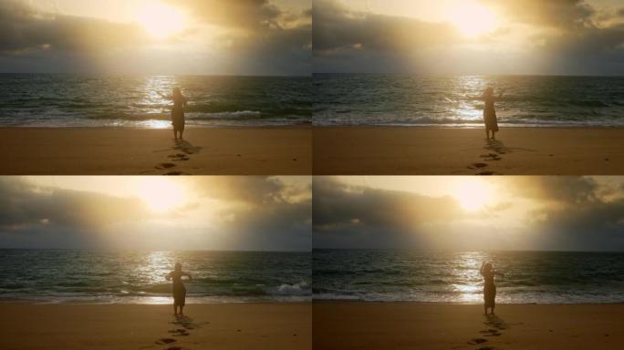 女人的WS剪影在日落时在海滩上表演慢舞动作