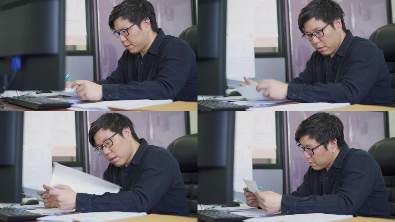 亚裔男子分析坐在办公室椅子上有关其工作的报道