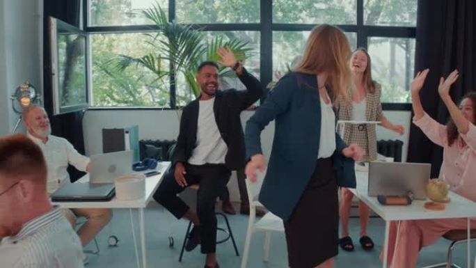 镜头跟随兴奋的年轻女老板进入办公室，与业务团队慢动作一起庆祝成功舞蹈。