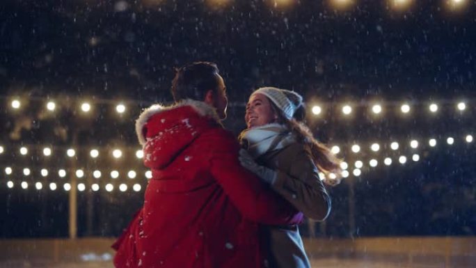 浪漫的冬天下雪的夜晚: 滑冰夫妇在溜冰场上玩得开心。双人滑冰男孩和恋爱中的女友，跳舞，牵手，拥抱，职