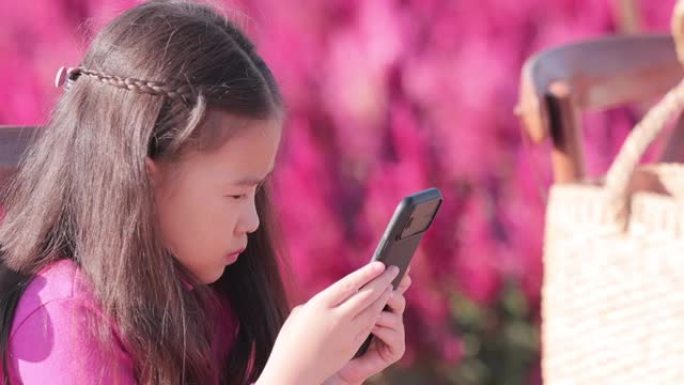SLO MO美丽的小女孩在美丽的公园使用智能手机
