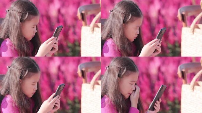 SLO MO美丽的小女孩在美丽的公园使用智能手机