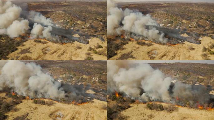 气候紧急情况。在非洲南部一个住宅区附近燃烧的草火的鸟瞰图。火灾是由干旱和气候变化引起的
