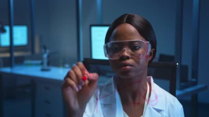 一位年轻的黑皮肤科学家，穿着一块玻璃板后面的白色实验室外套，她在那块板上写下化学式，然后微笑着看着镜