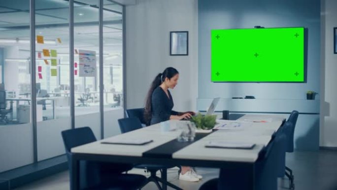 办公室会议室: 美丽的亚洲笔记本电脑专家与绿屏Choma Key Wall电视互动。在成长中的电子商