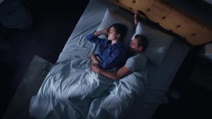 顶景公寓: 幸福的年轻夫妇晚上在床上拥抱在一起睡觉。漂亮的女朋友和帅气的男朋友睡在一起。两个家庭甜蜜