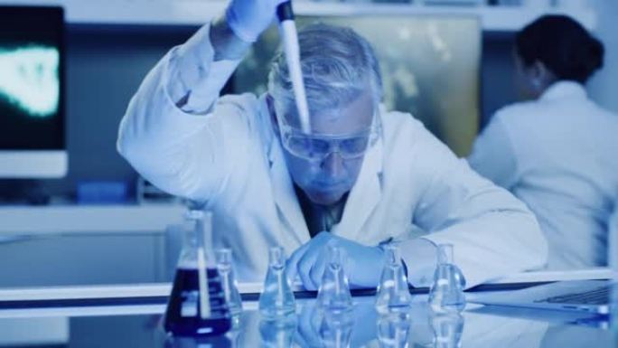 成熟的实验室科学家测试酚酞化学反应与烧杯和移液管在紫外线照明的实验室。认真的医生戴着防护眼镜，做碱性