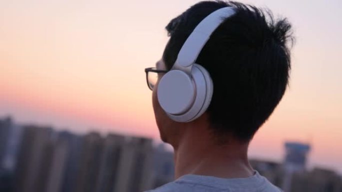 戴着耳机的男人在日落时听音乐