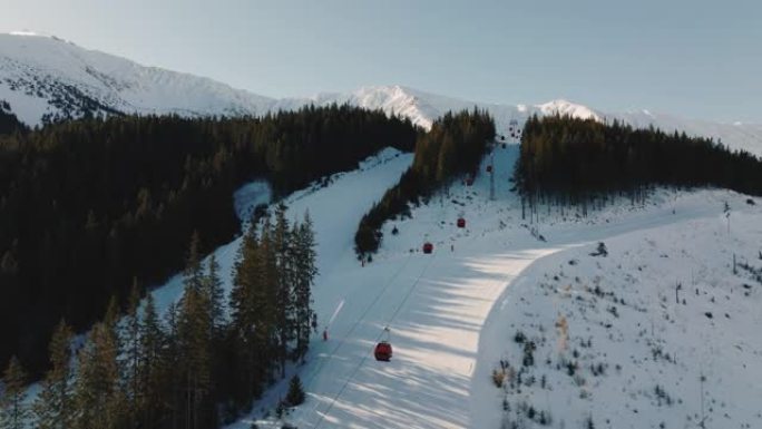 滑雪缆车在美丽的冬季风景山脉度假胜地的斜坡上上下移动，晴天太阳升起。