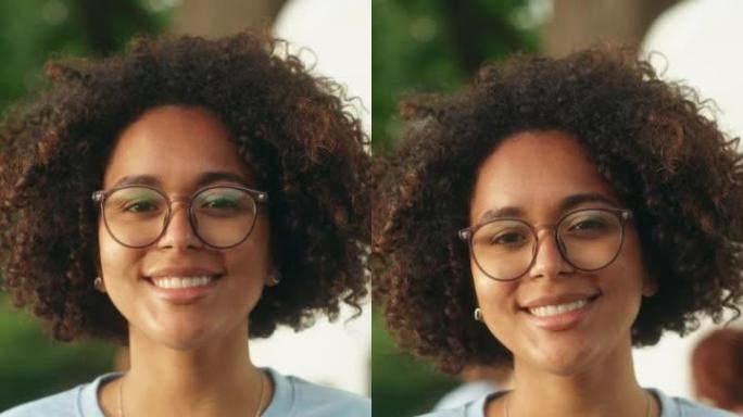 一位快乐乐于助人的黑人女性志愿者的垂直肖像。年轻的多民族拉丁人，非洲裔头发，戴着眼镜，微笑着，看着相