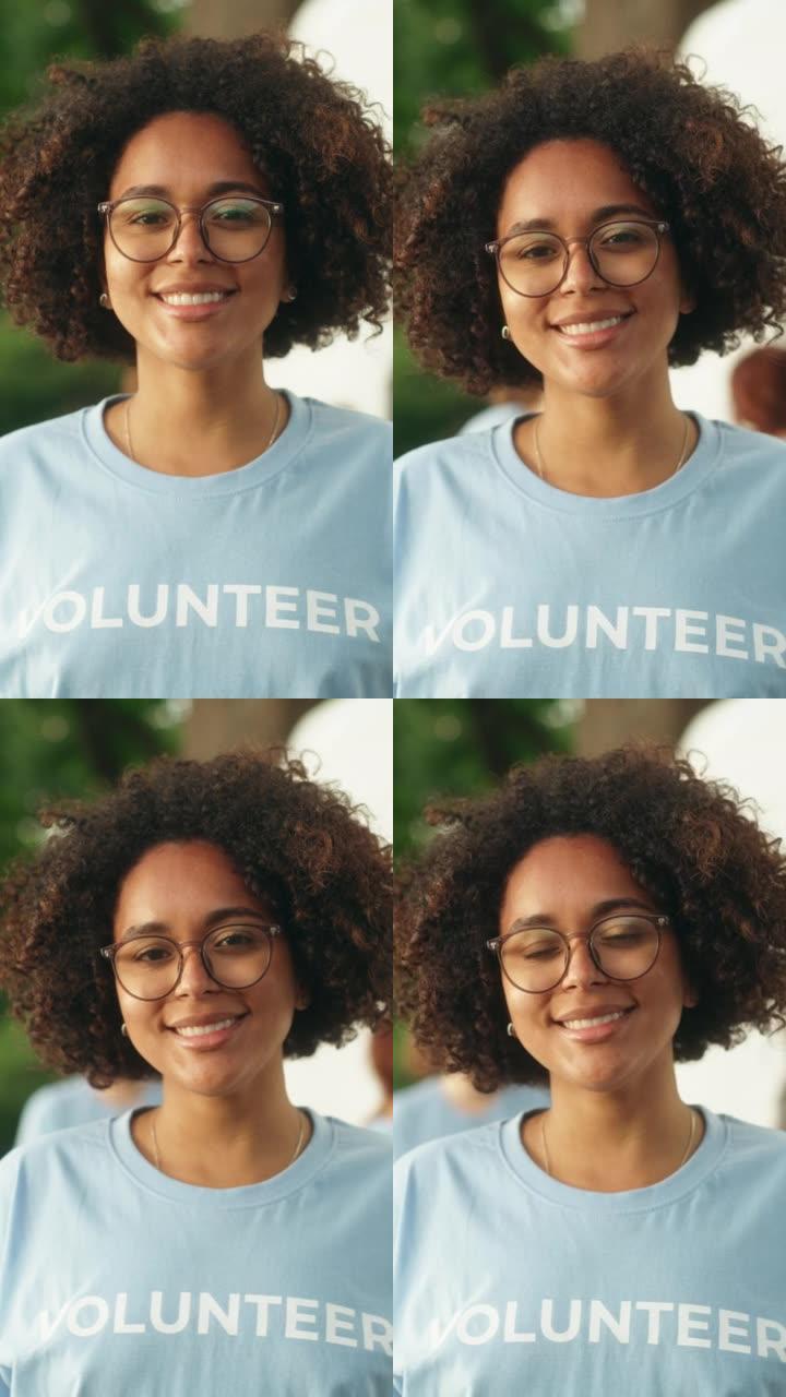 一位快乐乐于助人的黑人女性志愿者的垂直肖像。年轻的多民族拉丁人，非洲裔头发，戴着眼镜，微笑着，看着相
