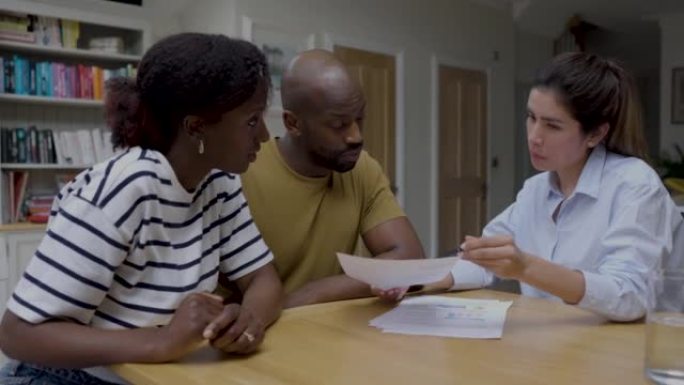 非裔美国夫妇与房地产经纪人交谈，并在买房时审查文书工作