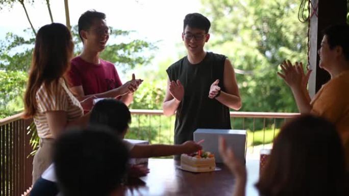 亚洲华裔男子在周末收到生日礼物，与朋友和家人在房子的后院庆祝生日