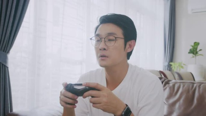 中等镜头4k分辨率有吸引力的亚洲成年人拿着操纵杆或游戏控制器，在家玩视频游戏机。人的反应享受他在游戏