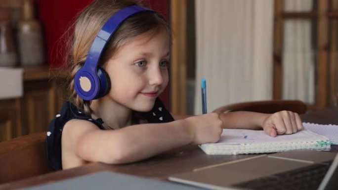 小女孩戴着耳机在笔记本电脑上学习听音频课程