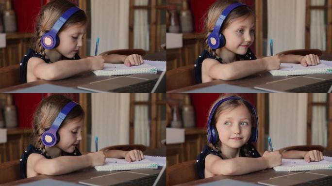 小女孩戴着耳机在笔记本电脑上学习听音频课程